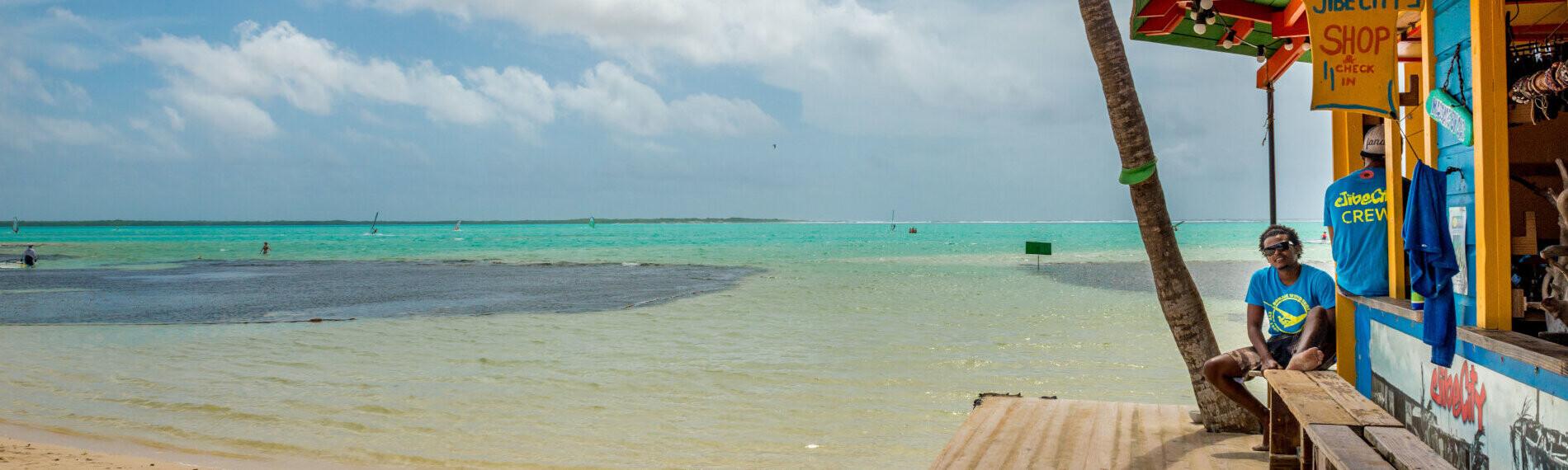 Jibe City, Bonaire - Strandbar mit Palme und Person, Blick aufs Meer.